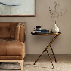 a table with a vase and some books on it next to a couch in a living room