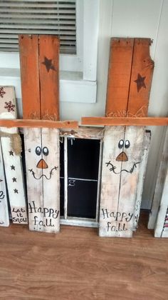 wooden pallets with faces painted on them sitting in front of a window