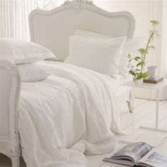 a bed with white sheets and pillows on it