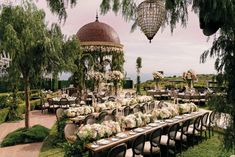 an outdoor dining area with tables, chairs and chandelier in the middle of it