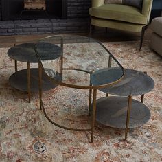 three tables sitting on top of a rug in front of a fire place with a couch