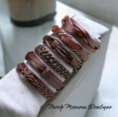 a stack of leather bracelets sitting on top of a white napkin next to a bottle