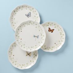 three white plates with butterflies on them against a blue background in the shape of circles