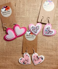 three pairs of heart shaped earrings are shown on a piece of cardboard with tags attached to them