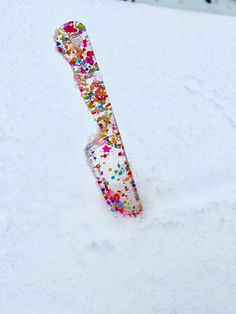 a snowboard sticking out of the snow with sprinkles on it's side