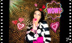 a woman is posing in front of a backdrop with hearts and zebra print on it