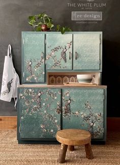 a cabinet with birds painted on it and a wooden stool in front of the door