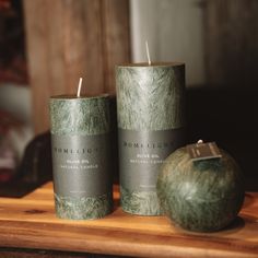 two green candles sitting on top of a wooden table