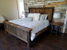 a bed with white sheets and pillows in a bedroom next to a wooden flooring