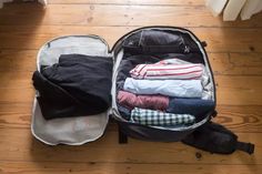 an open suitcase filled with clothes on top of a wooden floor