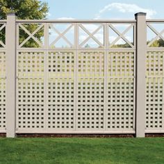 a white fence with lattice design in the grass