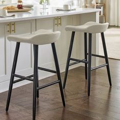 two bar stools sitting on top of a kitchen counter next to an island in front of a window