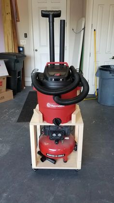 a red vacuum sitting on top of a wooden cart