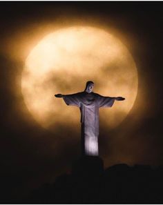 the statue of christ stands in front of a full moon with its arms spread out