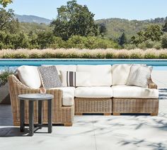 a wicker couch sitting on top of a patio next to a swimming pool