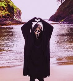 a person with their face painted like a ghost standing in the sand at the beach