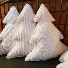 three white pillows sitting next to each other on top of a black tablecloth covered surface