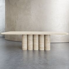 a long table with four columns in front of it on concrete floor next to wall