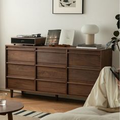 a living room with a large wooden dresser next to a lamp and pictures on the wall