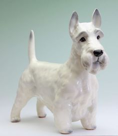 a white ceramic dog figurine on a light green background