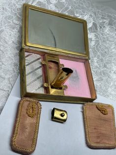 "Art Deco Leather-bound, book shape 1920 triple compact! Attached lipstick tube allows only the bottom to pull out and \"apply.\" It is hinged and easily raised by a push of a fingernail! The glass mirror throws a nice reflection even though it shows a bit of vintage wear. This beautiful compact has a metal medallion front and center that reads: \"Penna Military College Chester.\" Imprinted \"DBF.Co\" below mirror. There are two fitted puffs that each slide underneath two prongs to retain them w Book Shape, Vintage Lipstick Tube, Makeup Compact, Vintage Makeup Compact, Gold Compact Mirror Vintage, Vintage Mirror Compact, Vintage Powder Compacts, Lipstick Tube, Vanity Storage