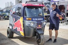 a man giving the thumbs up next to an electric vehicle with red bull painted on it