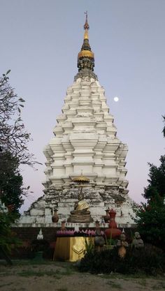 a very tall white building sitting in the middle of a field with trees around it