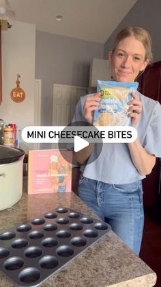 a woman holding up a bag of cheesecake bites next to a muffin pan