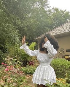 a woman in a white dress is taking a selfie with her cell phone outside