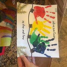 a child's hand holding up a piece of paper that has been made to look like a tree