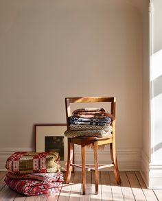 a wooden chair sitting on top of a hard wood floor next to a pile of blankets