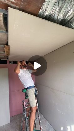 a man on a ladder painting the ceiling