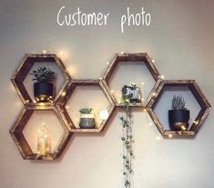 three hexagonal wooden shelves with plants and candles on them, hanging from the wall