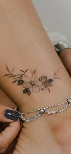 a woman with a tattoo on her stomach holding onto a chain that has flowers on it