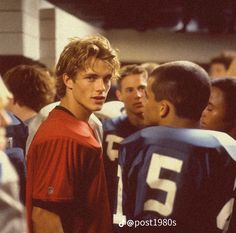 a group of young men standing next to each other in front of a crowd of people