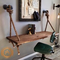 a wooden shelf with rope hanging from it's sides in front of a wall