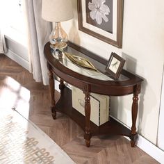 a wooden table with a glass top and two framed pictures on the wall behind it