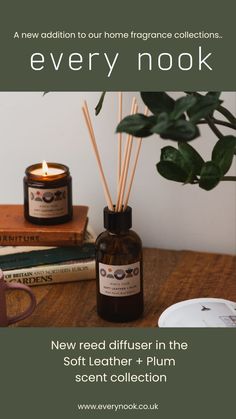 a bottle of reed diffuser next to a candle and some books on a table