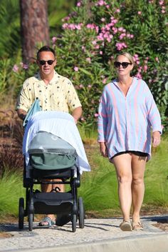 a man and woman walking with a baby in a stroller