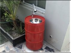 a large red barrel sitting next to a door with a faucet on it