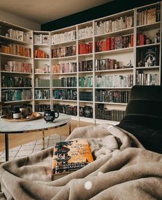 a living room with bookshelves full of books and a coffee table in the corner