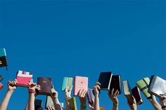 many people are holding books up in the air with their hands on top of each other