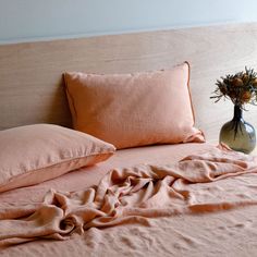 a bed with two pillows and a vase on the headboard in front of it