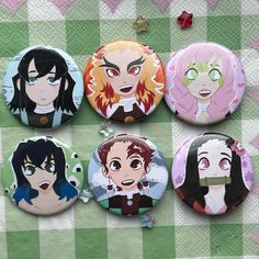 four anime buttons sitting on top of a green and white checkered table