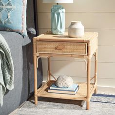 a small table with a vase on it next to a blue and white throw pillow