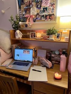 a laptop computer sitting on top of a wooden desk next to a lamp and pictures