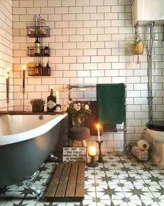 a bathroom with a bathtub, toilet and candles on the floor in front of it