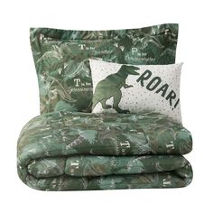 the dinosaur bedding is green and white with black lettering on it, along with two pillows