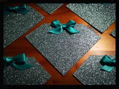 several pieces of silver and teal glitter with bows on them are arranged in squares