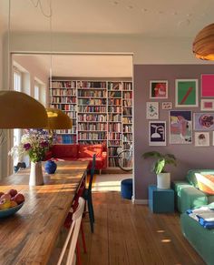 a living room filled with lots of furniture and bookshelves next to a dining table